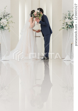A bride and groom kissing a vow in a chapel/church (wedding/bridal) A bride and groom kissing a vow in a chapel/church (wedding/bridal) 125603327