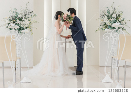 A bride and groom kissing a vow in a chapel/church (wedding/bridal) A bride and groom kissing a vow in a chapel/church (wedding/bridal) 125603328