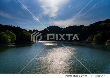 Clouds flowing on the ceaseless wind and reflections on the swaying lake surface at Nunome Dam with fresh greenery① 125603530