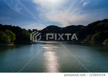 Clouds flowing on the ceaseless wind and reflections on the swaying lake surface at Nunome Dam with fresh greenery⑤ 125603534
