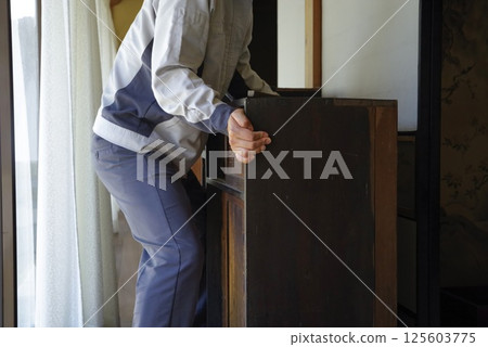 A man arranging furniture in his parents' home 125603775