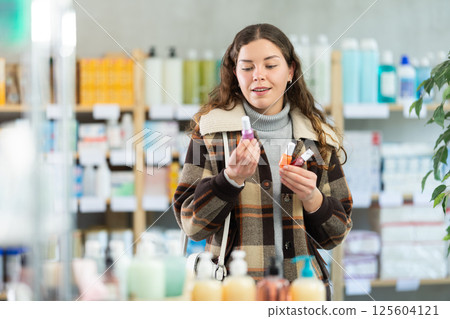 Female shopper chooses nailpolish in supermarket Female shopper chooses nailpolish in supermarket 125604121