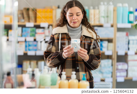 Girl in winter clothes looking for medicine in pharmacy 125604132
