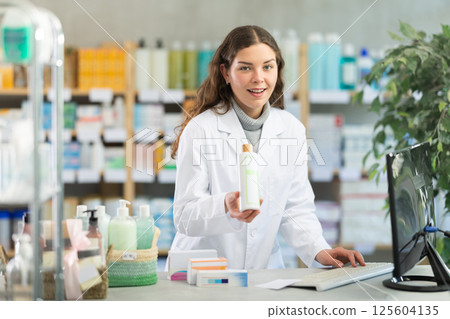 Young woman pharmacist offering shampoo 125604135
