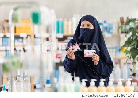 Young woman in hijab chooses paracetamol at pharmacy 125604148