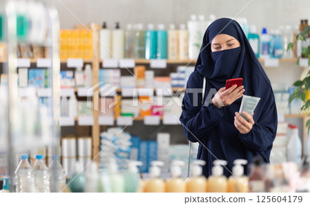 Young woman in hijab scanning qr code of cream 125604179