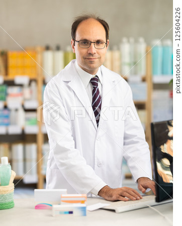 Male pharmacist working at computer in pharmacy 125604226