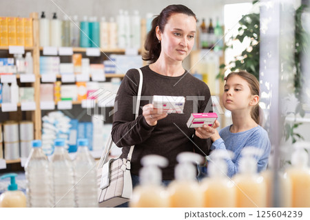 woman with a child chooses paracetamol at the pharmacy 125604239