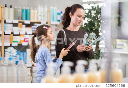 Woman with daughter choosing toothbrush in pharmacy Woman with daughter choosing toothbrush in pharmacy 125604266