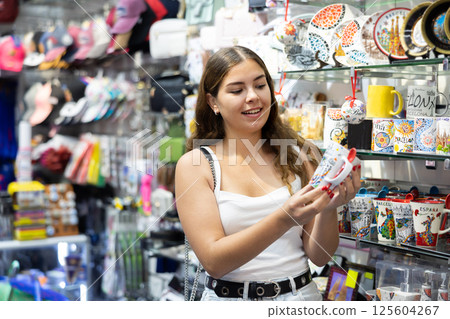 Female buyer holds in hands tests ceramic cup in memorable gifts shop Female buyer holds in hands tests ceramic cup in memorable gifts shop 125604267