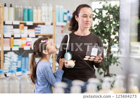 Woman with daughter choosing cosmetics in pharmacy 125604273