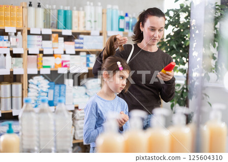 Woman chooses remedy for treating itchy scalp in child Woman chooses remedy for treating itchy scalp in child 125604310