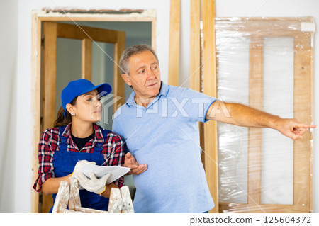 Woman repairer discussing repair works with man builder 125604372