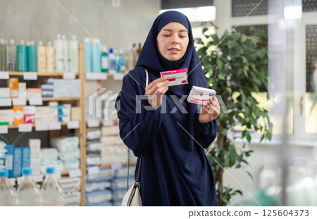 Young woman in hijab chooses paracetamol at pharmacy 125604373