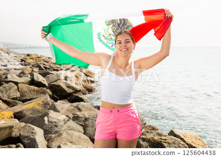 Young woman on coast posing with flag of Mexico Young woman on coast posing with flag of Mexico 125604438