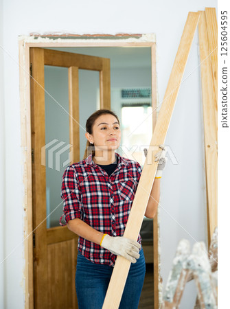 Woman carrying wooden planks during renovation works 125604595
