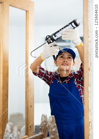 Cheerful woman construction worker using spray foam 125604610