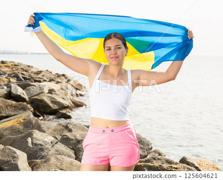 Young woman on coast posing with flag of Ukraine Young woman on coast posing with flag of Ukraine 125604621