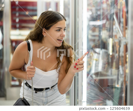 Interested young woman viewing various swords placed on display case Interested young woman viewing various swords placed on display case 125604639