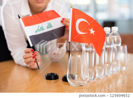 Little flag of Turkey on table and flag of Iraq put next to it by young woman 125604652