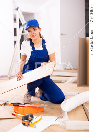 Female carpenter taking out laminate planks from package Female carpenter taking out laminate planks from package 125604653