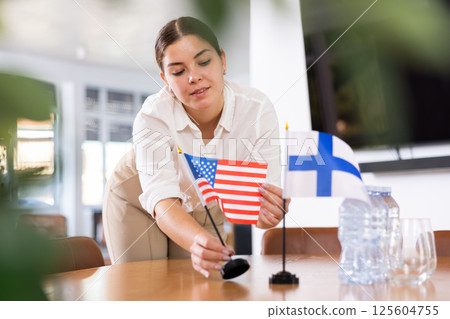female assistant prepares conference room for diplomats of Finland and USA female assistant prepares conference room for diplomats of Finland and USA 125604755