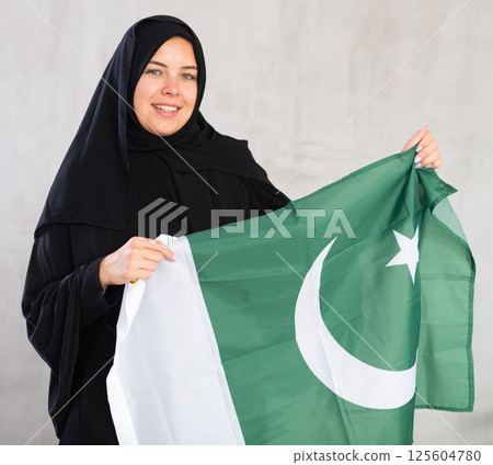 Happy young woman dressed in traditional islamic clothes with pakistani flag 125604780