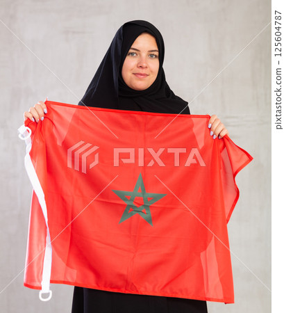Happy young woman dressed in traditional islamic clothes with moroccan flag 125604787