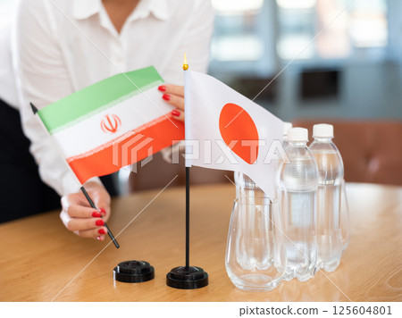 Little flag of Japan on table and flag of Iran put next to it by young woman 125604801