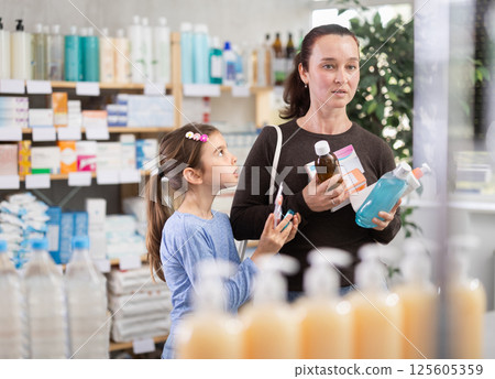 woman keeps various goods, vitamins in a pharmacy with her daughter 125605359