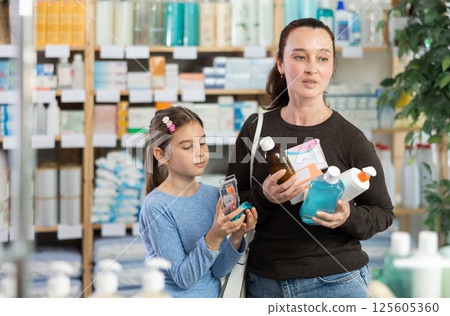 Woman with daughter choosing medicines and hygiene products 125605360