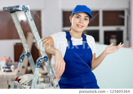 Portrait of young woman builder making presenting gesture Portrait of young woman builder making presenting gesture 125605364