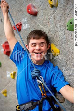 Young Climber Enjoys Rock Climbing at an Indoor Gym, Showcasing Strength and Confidence While Smiling 125605853
