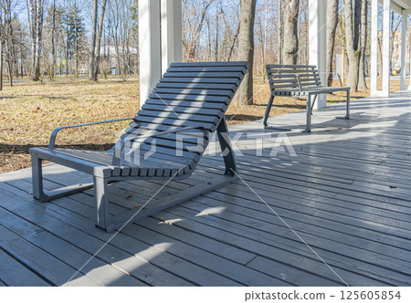 Empty grey wooden deck chairs or sun beds in city park. Concept of recreation, tanning 125605854