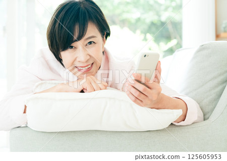 Middle woman looking at a smartphone on the sofa 125605953