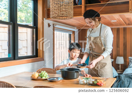 Family staying in a bungalow/cottage and preparing meals together (family trip/glamping) 125606092