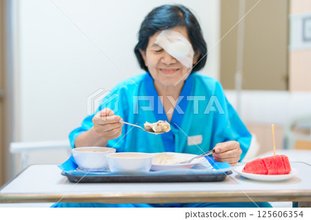 Senior Woman eating food after eye surgery in hospital . Eye disease, Cataract, Glaucoma, Age Related Macular Degeneration, Diabetic Retinopathy, Lasik, World Glaucoma day and health treatment Senior Woman eating food after eye surgery in hospital . Eye disease, Cataract, Glaucoma, Age Related Macular Degeneration, Diabetic Retinopathy, Lasik, World Glaucoma day and health treatment 125606354