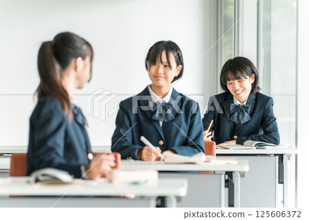 Elementary school students, junior high school students, high school students, and female high school students (friends) talking to students sitting behind them during class at school Elementary school students, junior high school students, high school students, and female high school students (friends) talking to students sitting behind them during class at school 125606372