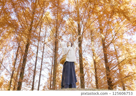 Middle-aged woman taking a deep breath among autumn leaves 125606753