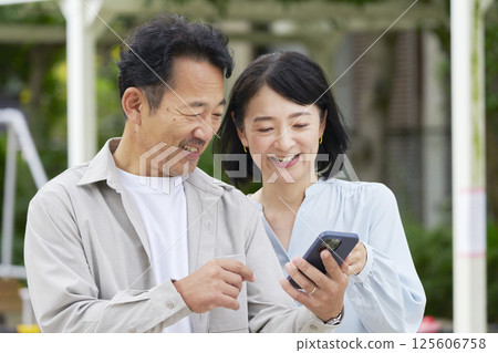Middle-aged couple using smartphone outdoors Middle-aged couple using smartphone outdoors 125606758