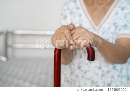 Asian elderly disability woman holding waling stick, wood cane, round handle, walking aid for help to walk. 125606921