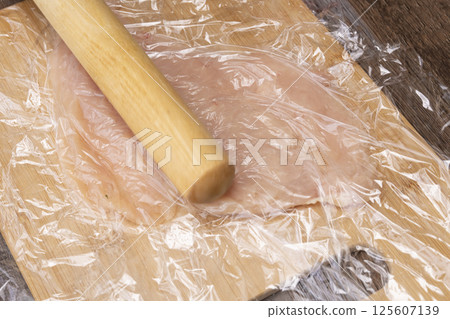 The process of making chicken ham: Pound, stretch, roll and boil chicken breast meat. 125607139