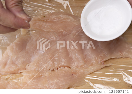 The process of making chicken ham: Pound, stretch, roll and boil chicken breast meat. 125607141