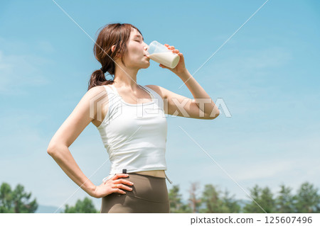 婦女在運動時飲用蛋白質/EAA 飲料(藍天) 婦女在運動時飲用蛋白質/EAA 飲料(藍天) 125607496