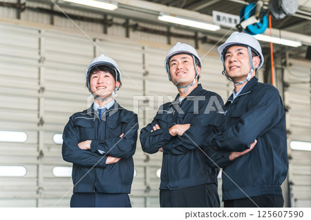 Male worker/businessman in work clothes standing in a factory/warehouse Male worker/businessman in work clothes standing in a factory/warehouse 125607590