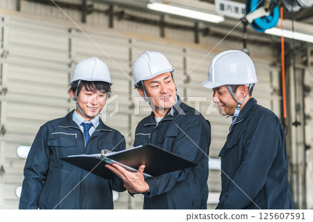 Male worker having a meeting at a factory, warehouse, or logistics center (process management) Male worker having a meeting at a factory, warehouse, or logistics center (process management) 125607591