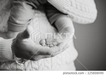 Black and White Close-Up of Adult Holding Baby's Feet 125608040
