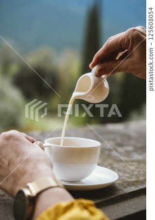 Pouring Milk into Coffee Cup on Outdoor Balcony 125608054