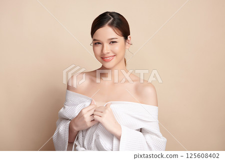A beautiful young Asian woman with clean, fresh skin against a beige background. Skincare, facial treatment, cosmetology, beauty, and spa. An elegant portrait of an Asian woman. A beautiful young Asian woman with clean, fresh skin against a beige background. Skincare, facial treatment, cosmetology, beauty, and spa. An elegant portrait of an Asian woman. 125608402