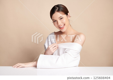 A beautiful young Asian woman with clean, fresh skin against a beige background. Skincare, facial treatment, cosmetology, beauty, and spa. An elegant portrait of an Asian woman. A beautiful young Asian woman with clean, fresh skin against a beige background. Skincare, facial treatment, cosmetology, beauty, and spa. An elegant portrait of an Asian woman. 125608404
